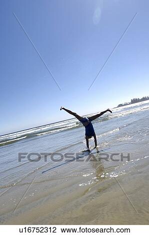 Stock Image - Pre-teen girl performing cartwheel on beach, Vancouver Island, Canada. Fotosearch