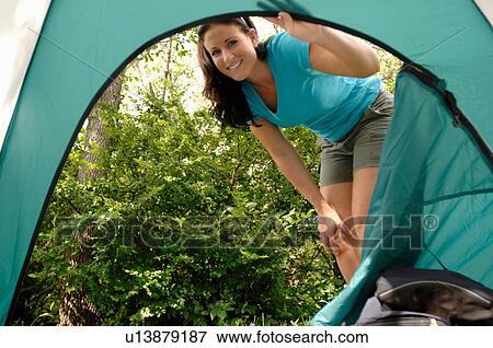 Stock Photo - Young woman looking into opening of tent, Regina, Saskatchewan. Fotosearch