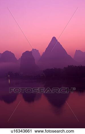 Stock Image - China, Guangxi Province, Guilin, Yangshuo, Li River with mountain at sunrise. Fotosearch
