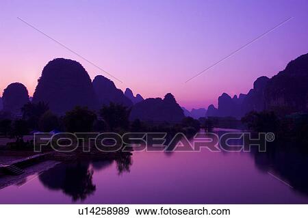 Stock Photo - China, Guangxi Province, Guilin, Yangshuo, Yulong River with mountains at sunset. Fotosearch