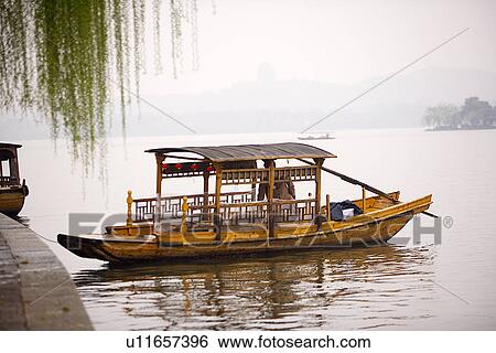 Stock Photograph - China, Zhejiang Province, Hangzhou, row boat moored by lakeside. Fotosearch