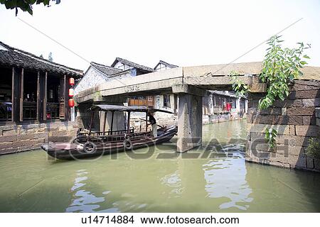 Picture - Asia, China, Zhejiang Province, A boat makes its way through Wuzhen water town. Fotosearch