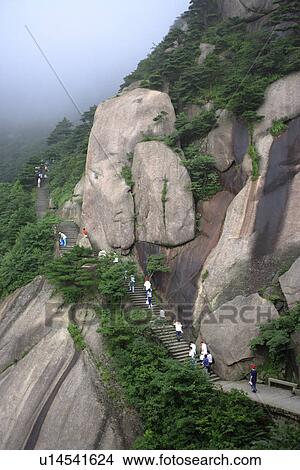 Picture - China, Anhui, Mt. Huangshan, Tourists walking up steps on side of mountain. Fotosearch