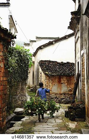 Stock Photo - Man carrying grasses, Cheng Kan Village, Anhui Province, China, Asia. Fotosearch