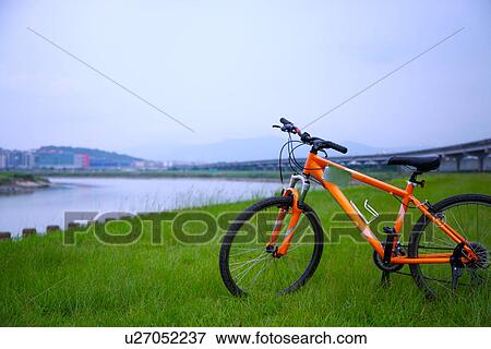 Stock Photo - Bicycle on grass by stream. Fotosearch