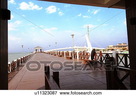 Stock Photo - Pier with bridge in the background, Lovers Bridge, Danshui, Taipei, Taiwan. Fotosearch