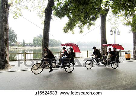 Stock Image - Tourists traveling in rickshaws, Beijing, China. Fotosearch