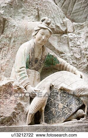 Stock Image - A stone carving showing the story of a hen-raising woman, The Dazu Rock Carvings, Chongqing, China. Fotosearch