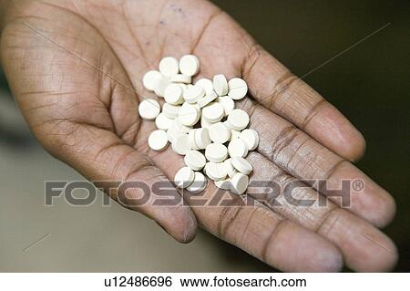 Stock Photograph - A closeup of a hand holds AIDS pills at the Pepo La Tumaini Jangwani, HIV/AIDS Community Rehabilitation Program, Orphanage & Clinic. Pepo La Tumaini Jangwani (wind of hope in the arid place) offers hope, support and care for orphan and vulnerable childre. Fotosearch