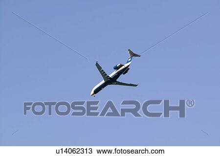 Stock Image - Commercial jet airplane flies overhead in a clear blue sky.. Fotosearch