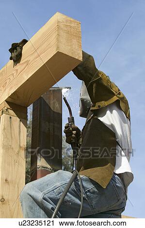 Stock Image - Glowing light of welder welding steel beam on California home. Fotosearch