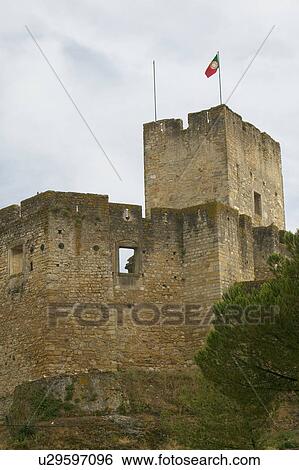 Stock Photograph - Portuguese flag flies over Castle wall at the Templar Castle and the Convent of the Knights of Christ, founded by Gualdim Pais in 1160 AD, is a Unesco World Heritage Site in Tomar, Portugal. Fotosearch
