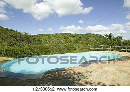 Stock Image - Swimming pool with turquoise water surrounded by the hills of North Kenya, Africa at the Lewa Wildlife Conservancy. Fotosearch