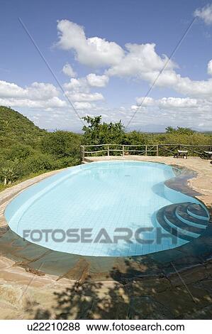 Stock Photo - Swimming pool with turquoise water surrounded by the hills of North Kenya, Africa at the Lewa Wildlife Conservancy. Fotosearch