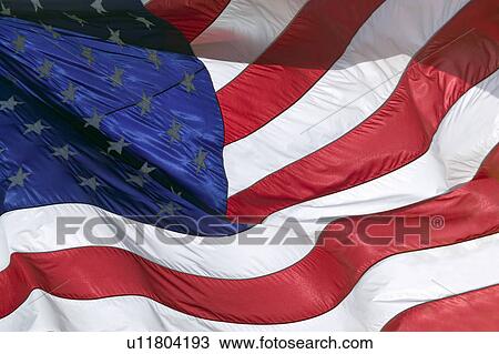 Stock Image - The stars and stripes, and red, white and blue colors of a US Flag blow in the wind.. Fotosearch