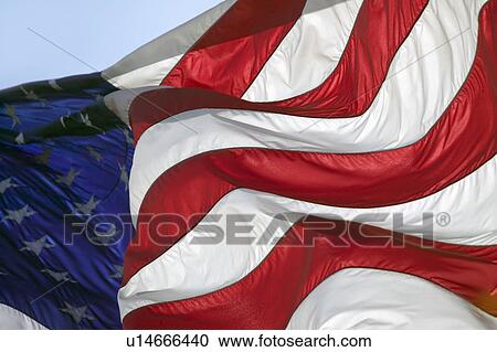 Stock Image - The stars and stripes, and red, white and blue colors of a US Flag blow in the wind.. Fotosearch