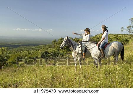 Two female horseback riders on horseback ride at sunset overlooking Lewa Wildlife Conservancy in North Kenya, Africa View Large Photo Image Stock Image - Two female horseback riders on horseback ride at sunset overlooking Lewa Wildlife Conservancy in North Kenya, Africa. Fotosearch