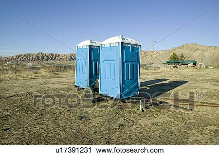 Stock Image - Two out houses, mobile blue bathrooms, sit on trailer in the middle of a field in Ventura County, California off of highway 33 near Cuyama. Fotosearch
