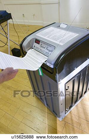 Stock Photo - Voter inserts completed ballot for Congressional election, November 2006, into an electronic scanner in Ojai, Ventura County, California. Fotosearch