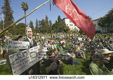 A cutout of George W. Bush saying "Mission Accomplished" is seen with a crowd of protesters and a red peace flag at an anti-Iraq War protest march in Santa Barbara, California on March 17, 2007 View Large Photo Image Stock Image - A cutout of George W. Bush saying "Mission Accomplished" is seen with a crowd of protesters and a red peace flag at an anti-Iraq War protest march in Santa Barbara, California on March 17, 2007. Fotosearch