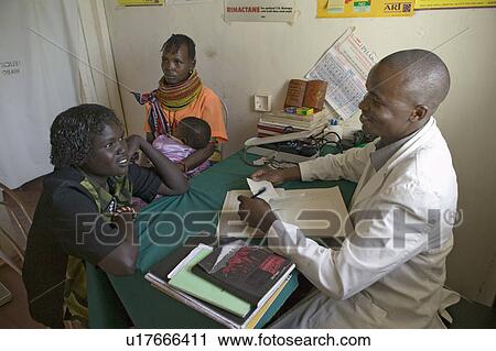 Stock Image - A doctor consults with mother and children about HIV/AIDS at Pepo La Tumaini Jangwani, HIV/AIDS Community Rehabilitation Program, Orphanage & Clinic. Pepo La Tumaini Jangwani (wind of hope in the arid place) offers hope, support and care for orphan and v. Fotosearch
