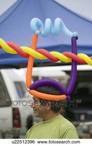 A Hispanic man wares multi-colored balloons on his head at farmers market in Santa Barbara California View Large Photo Image Stock Photograph - A Hispanic man wares multi-colored balloons on his head at farmers market in Santa Barbara California. Fotosearch