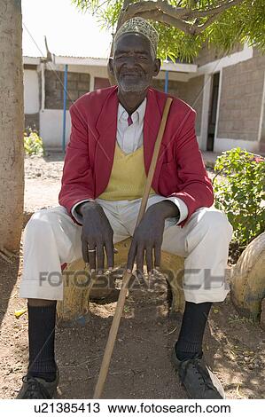 Stock Image - A Kenyan man sits with red jacket on at the Pepo La Tumaini Jangwani, HIV/AIDS Community Rehabilitation Program, Orphanage & Clinic. Pepo La Tumaini Jangwani (wind of hope in the arid place) offers hope, support and care for orphan and vulnerable childre. Fotosearch