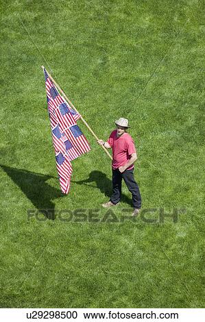Stock Image - A patriotic man with a US Flag made of many US Flags stands alone in a green grass lawn at an anti-Iraq War protest march in Santa Barbara, California on March 17, 2007. Fotosearch