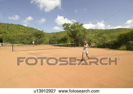 Stock Photo - A tourist couple enjoy a game of outdoor tennis at Lewa Downs in North Kenya, Africa. Tourism has taken a significant leap forward for local communities who now run various safari lodges and camps like the one at Lewa Wildlife Conservancy. This provides . Fotosearch