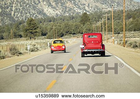 A yellow and red VW hotrod drives in opposite direction of a restored bright Red Roadster hotrod pickup truck along rural highway in Kern County near Lockwood Valley, CA View Large Photo Image Stock Photo - A yellow and red VW hotrod drives in opposite direction of a restored bright Red Roadster hotrod pickup truck along rural highway in Kern County near Lockwood Valley, CA. Fotosearch