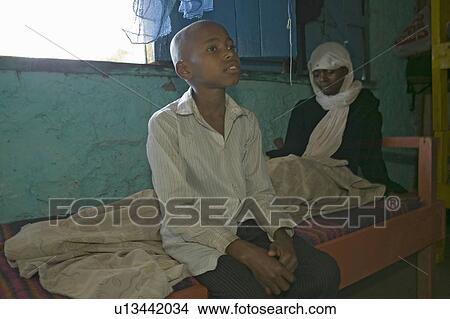 A young boy sits at the bedside of his mother who is infected with HIV/AIDS at Pepo La Tumaini Jangwani, HIV/AIDS Community Rehabilitation Program, Orphanage & Clinic. Pepo La Tumaini Jangwani (wind of hope in the arid place) offers hope, support and car View Large Photo Image Picture - A young boy sits at the bedside of his mother who is infected with HIV/AIDS at Pepo La Tumaini Jangwani, HIV/AIDS Community Rehabilitation Program, Orphanage & Clinic. Pepo La Tumaini Jangwani (wind of hope in the arid place) offers hope, support and car. Fotosearch