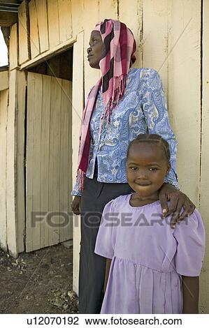 Stock Image - A young Kenya girl, infected with HIV/AIDS, stands beside Khadija Rama, founder of Pepo La Tumaini Jangwani, HIV/AIDS Community Rehabilitation Program, Orphanage & Clinic. Pepo La Tumaini Jangwani (wind of hope in the arid place) offers hope, support and. Fotosearch