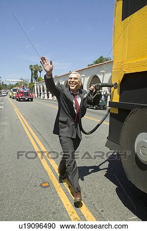 Stock Image - Actor impersonating George W. Bush pumping gas into a Hummer vehicle makes its way down main street during a Fourth of July parade in Ojai, CA. Fotosearch