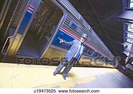 Stock Photography - Angled view of conductor at Amtrak train platform announces "All Aboard" at East Coast train station on the way to New York City, New York, Manhattan, New York. Fotosearch