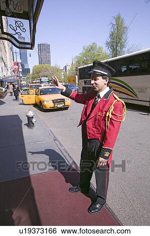 Stock Photograph - Bellman in red jacket calls for cab in front of Helmsley Park Lane Hotel on Central Park West, in Manhattan, New York City, New York. Fotosearch
