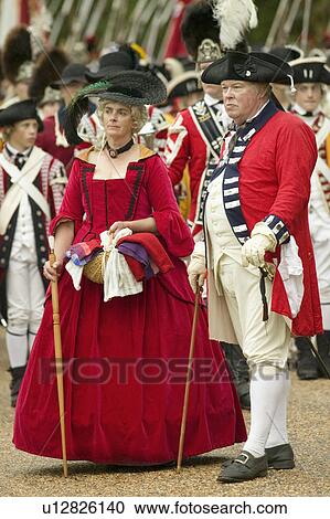 Stock Image - British officer and lady in red dress watch with disdain the British surrender to General George Washington at the 225th Anniversary of the Victory at Yorktown, a reenactment of the siege of Yorktown, where General George Washington commanded 17, 600 Ameri. Fotosearch