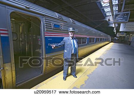 Stock Photo - Conductor at Amtrak train platform announces "All Aboard" at East Coast train station on the way to New York City, New York, Manhattan, New York. Fotosearch