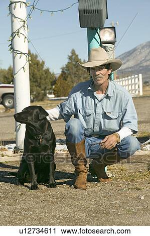 Stock Image - Cowboy with his dog kneel down at the Sands Motel at the intersection of Route 54 & 380 in Carrizozo, New Mexico. Fotosearch