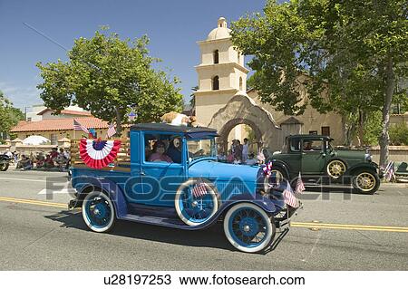 Stock Image - Festive decorated antique automobile makes its way down main street during a Fourth of July parade in Ojai, CA. Fotosearch