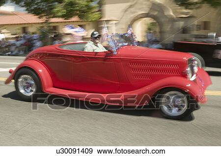 Stock Photo - Festive decorated antique automobile makes its way down main street during a Fourth of July parade in Ojai, CA. Fotosearch
