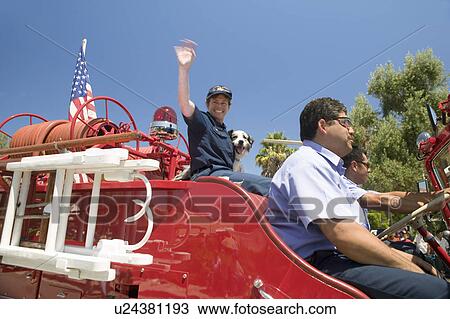 Stock Image - Fire truck and firefighters with dog make their way down main street during a Fourth of July parade in Ojai, CA. Fotosearch