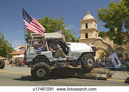 Stock Image - Flag adorned jeep demonstrates 4 wheel maneuvers as it makes its way down main street during a Fourth of July parade in Ojai, CA. Fotosearch