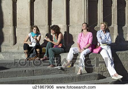 Stock Photograph - Four women relax in sunlight of old Barcelona in Barri Gotic area, the Gothic Quarter, Spain. Fotosearch