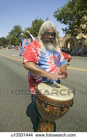 Hippie in red, white and blue tie-dye t-shirt pounds his drum down main street during a Fourth of July parade in Ojai, CA View Large Photo Image Picture - Hippie in red, white and blue tie-dye t-shirt pounds his drum down main street during a Fourth of July parade in Ojai, CA. Fotosearch