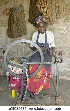 Stock Photography - Masai woman weaves rug as part of a community based business at the Lewa Foundation in North Kenya, Africa. Community conservation programs have been at the forefront of long term sustainable development activities at Lewa Downs. Furniture, rugs and carp. Fotosearch