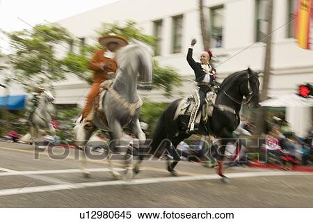Stock Photography - Mexican horseback riders trot along during the opening day parade down State Street of Old Spanish Days Fiesta held every August in Santa Barbara, California. Fotosearch