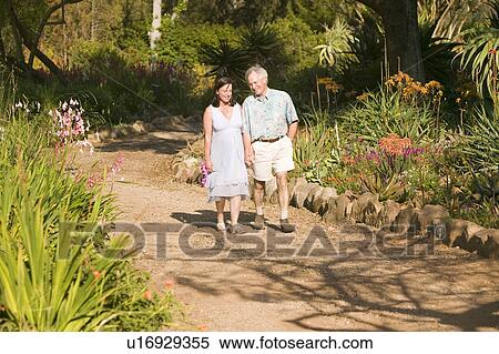 Stock Photography - Middle-aged husband walks down springtime path with his pregnant wife in gardens in Ojai, California. Fotosearch