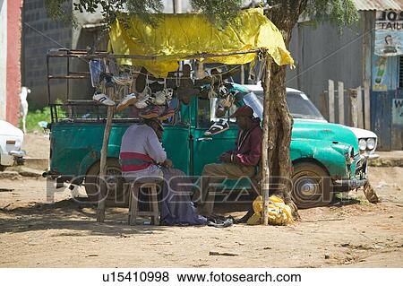 Stock Photo - Old pickup truck and local people sit in shade in the Great Rift Valley, near Nairobi, Kenya, Africa. Fotosearch