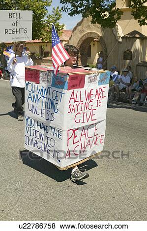 Parade participants carrying signs about peace make their way down main street during a Fourth of July parade in Ojai, CA View Large Photo Image Stock Photo - Parade participants carrying signs about peace make their way down main street during a Fourth of July parade in Ojai, CA. Fotosearch