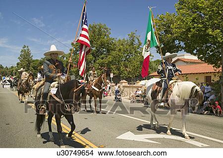 Parade participants on horseback carrying American and Mexican flags make their way down main street during a Fourth of July parade in Ojai, CA View Large Photo Image Picture - Parade participants on horseback carrying American and Mexican flags make their way down main street during a Fourth of July parade in Ojai, CA. Fotosearch